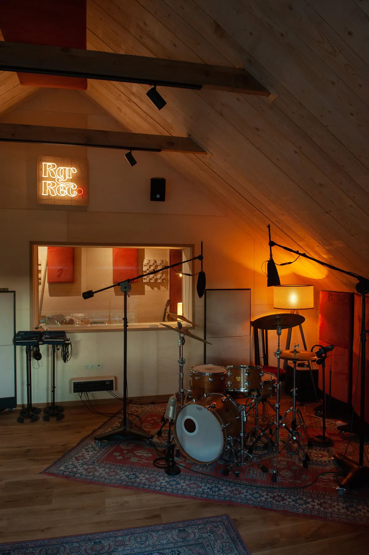De opnameruimte van Roger Recording met drumstel, microfoons en warme verlichting