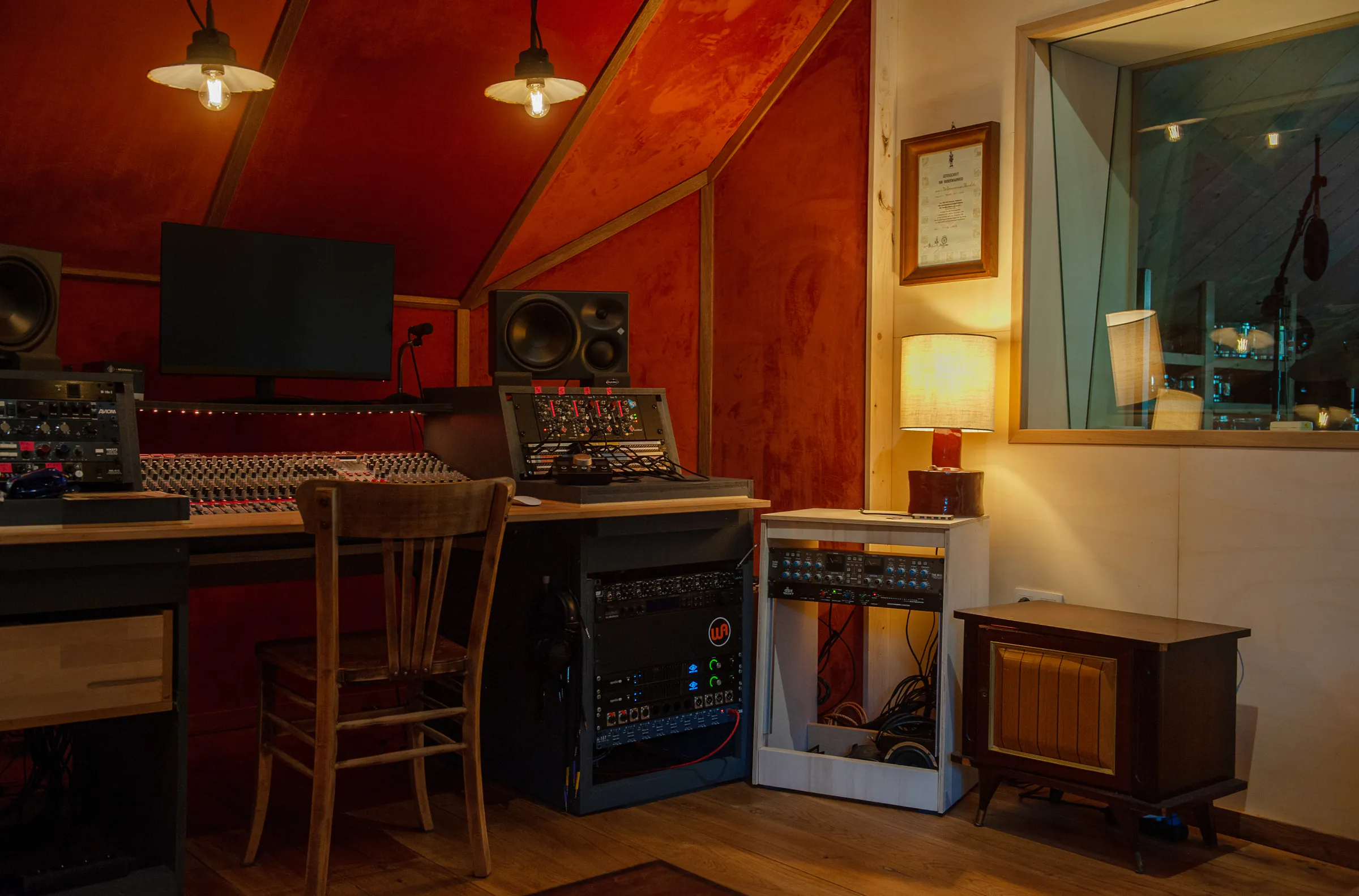De control room met mengtafel, monitors en analoge apparatuur
